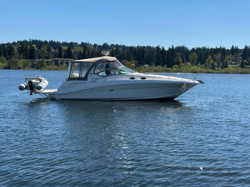 Slide: The Image of 2004 Sea Ray 340 Sundancer yacht cruising on a serene lake under clear skies. - 1
