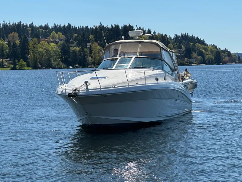 Slide: The Image of 2004 Sea Ray 340 Sundancer cruising on a serene lake with forested shoreline. - 2