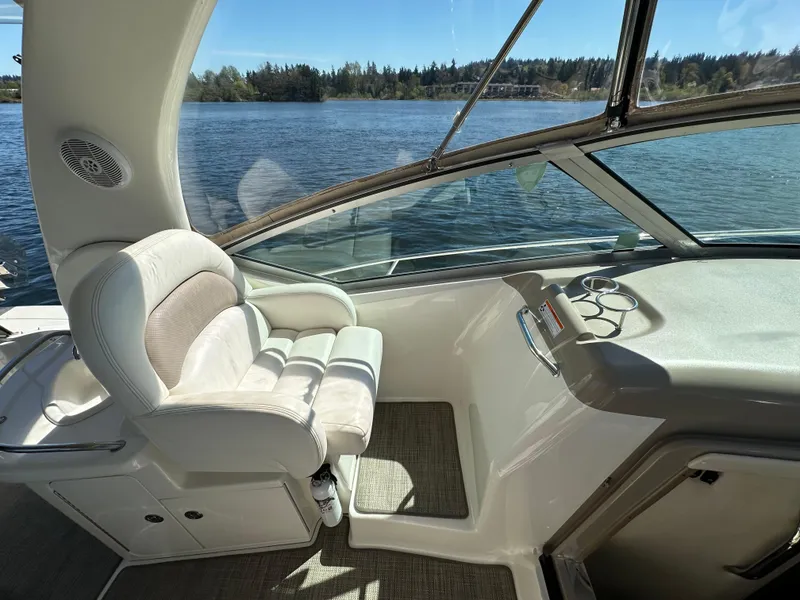 Slide: The Image of 2004 Sea Ray 340 Sundancer cockpit with white seating, overlooking serene lake and forest. - 25