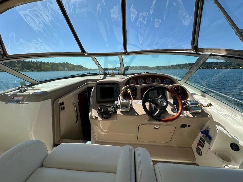 Slide: The Image of 2004 Sea Ray 340 Sundancer helm with steering wheel and navigation system on a sunny day. - 26
