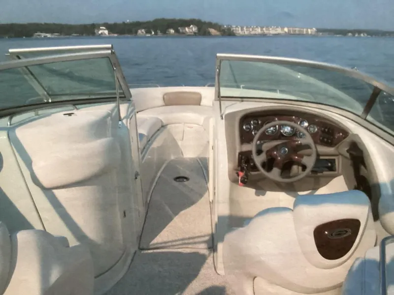 Slide: The Image of 2006 Crownline 270 BR boat interior with steering wheel, open water view. - 2