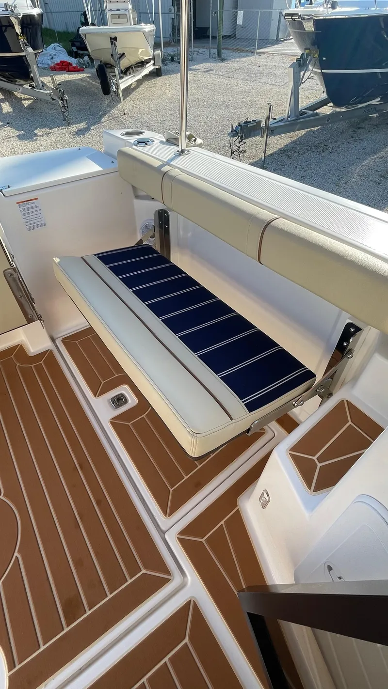 Slide: The Image of 2023 Ranger Tugs R-27 boat interior with foldable seating and wood-patterned flooring. - 10