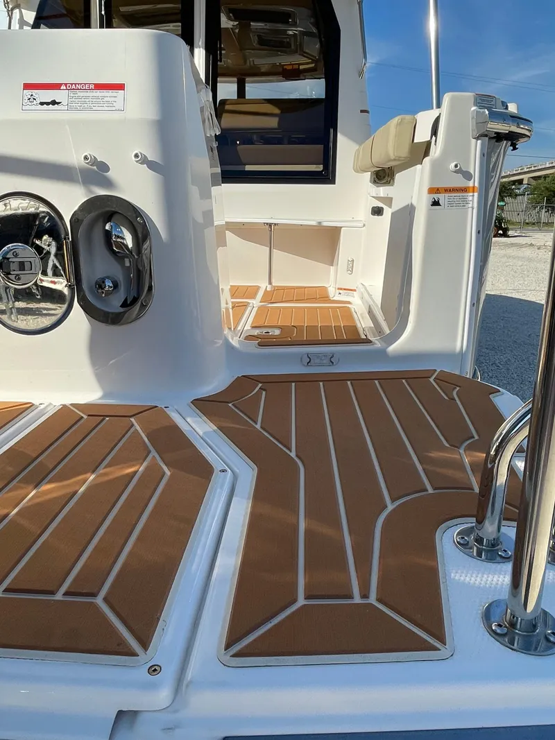 Slide: The Image of 2023 Ranger Tugs R-27 boat deck with teak-style flooring and stainless steel fixtures. - 14