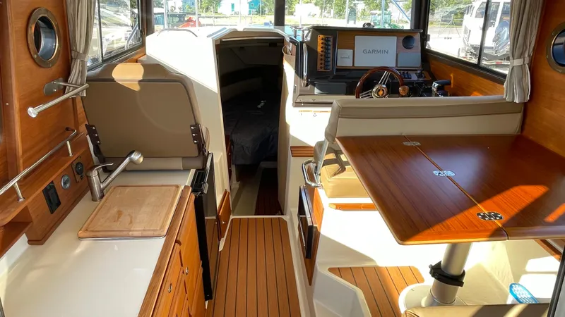 Slide: The Image of 2023 Ranger Tugs R-27 interior with wood finishes, kitchenette, and seating area. - 16