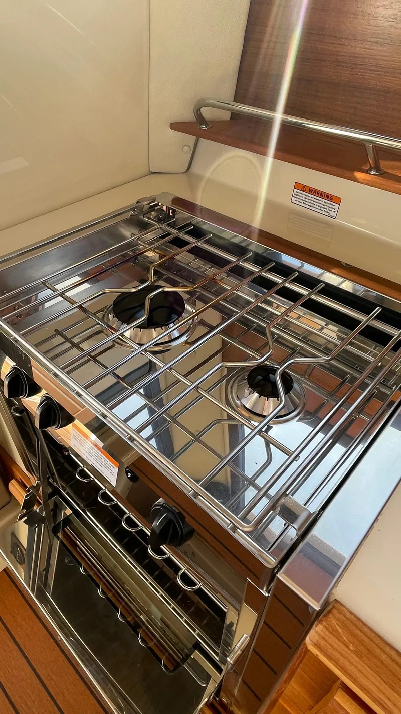 Slide: The Image of 2023 Ranger Tugs R-27 boat kitchen with stainless steel stove and oven. - 19