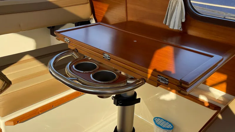 Slide: The Image of 2023 Ranger Tugs R-27 interior with wooden table and stainless steel cup holders. - 21