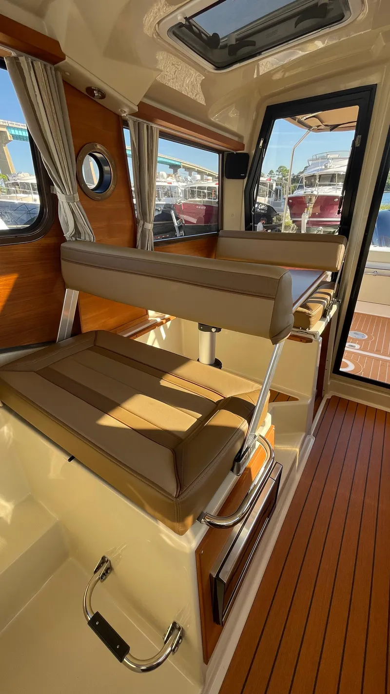 Slide: The Image of 2023 Ranger Tugs R-27 interior with wood accents and brown seating. - 24