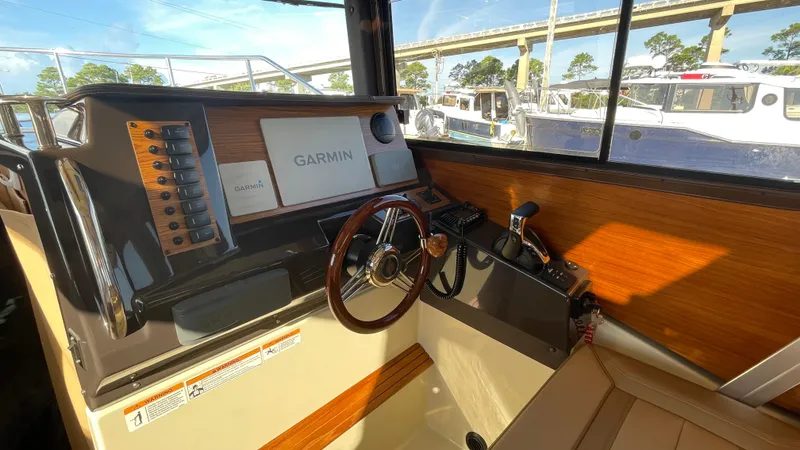 Slide: The Image of 2023 Ranger Tugs R-27 helm with Garmin navigation system and wooden steering wheel. - 25