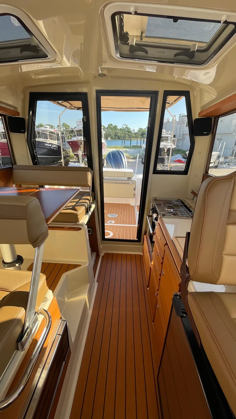 Slide: The Image of 2023 Ranger Tugs R-27 interior with wood flooring and seating, showcasing a modern, compact design. - 30