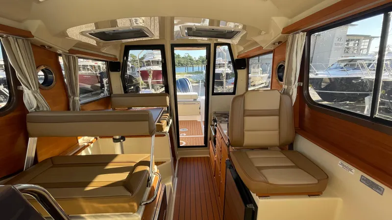 Slide: The Image of 2023 Ranger Tugs R-27 interior with seating, wood accents, and large windows. - 31