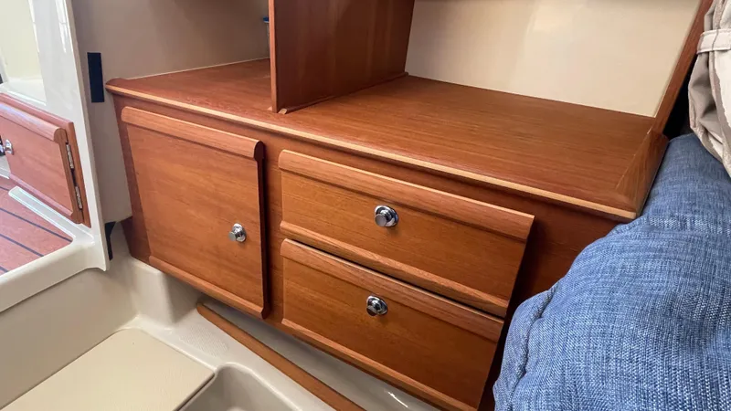 Slide: The Image of 2023 Ranger Tugs R-27 interior with wooden cabinets and drawers, featuring sleek design and chrome handles. - 37