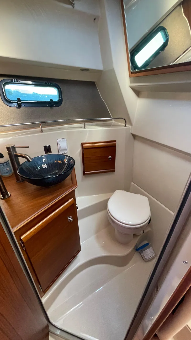 Slide: The Image of 2023 Ranger Tugs R-27 boat bathroom with modern sink, toilet, and wooden cabinetry. - 39