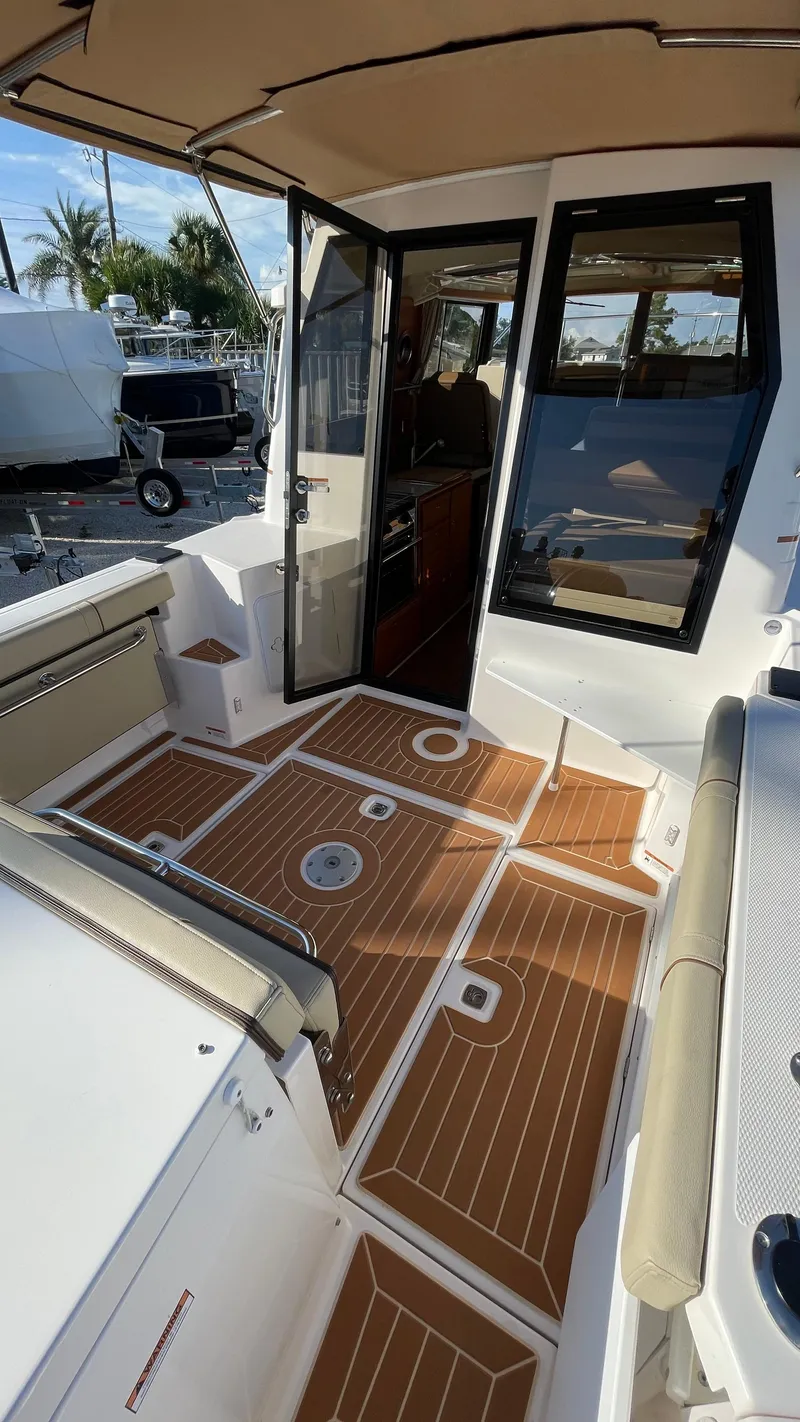 Slide: The Image of 2023 Ranger Tugs R-27 boat deck with teak flooring and open cabin door. - 4