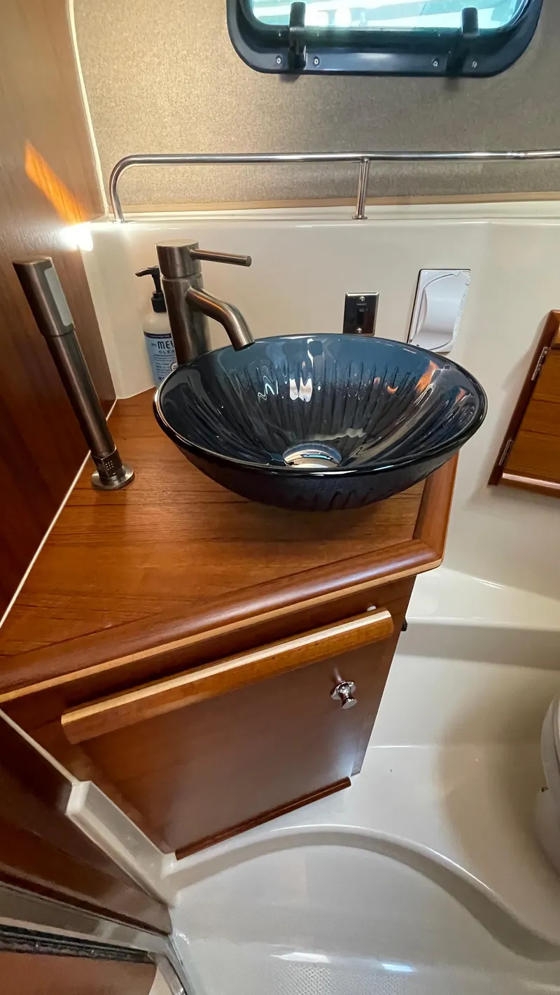 Slide: The Image of 2023 Ranger Tugs R-27 bathroom with elegant black vessel sink and wooden cabinetry. - 40