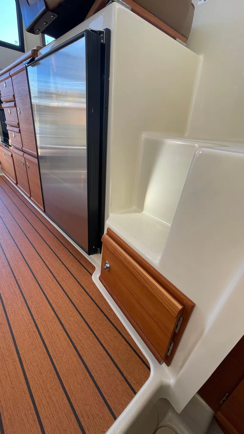 Slide: The Image of 2023 Ranger Tugs R-27 interior with wood flooring and compact kitchen area. - 44