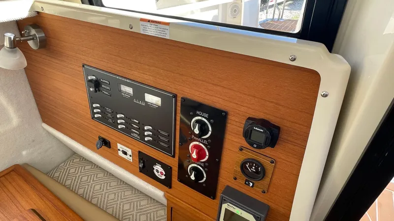 Slide: The Image of Control panel of 2023 Ranger Tugs R-27 boat with wood finish and various switches. - 47