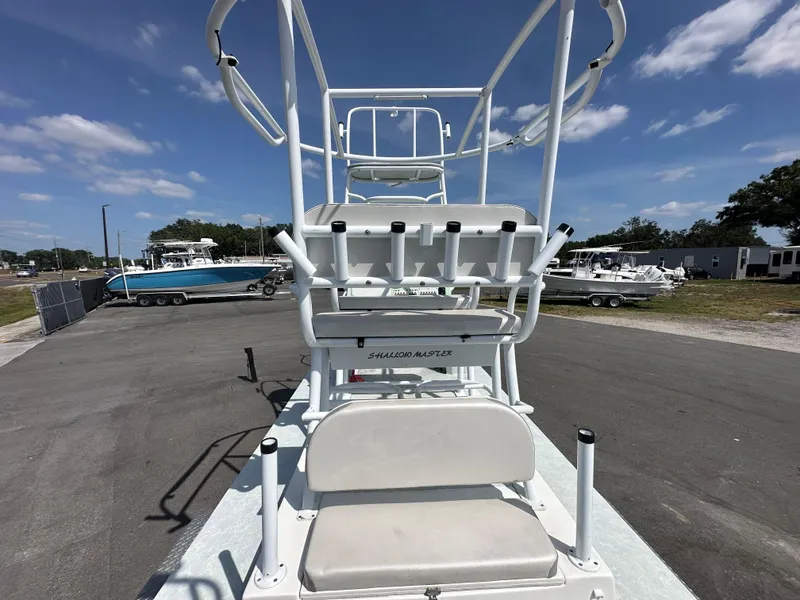Slide: The Image of 2023 Shallow Master 240 SMS boat with elevated seating, parked outdoors under a clear sky. - 16