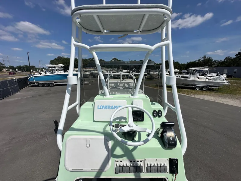 Slide: The Image of Shallow Master 240 SMS 2023 boat dashboard with steering wheel and controls, marina background. - 19