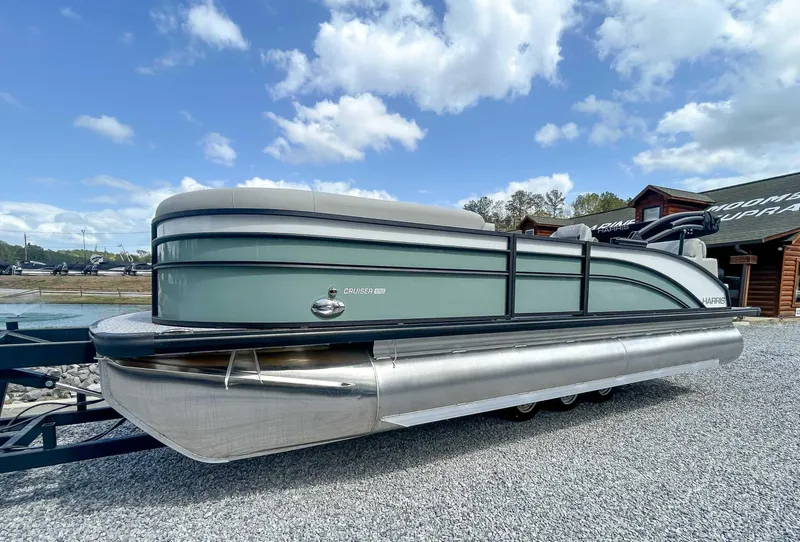 Slide: The Image of 2025 Harris CRUISER 230 SLDH pontoon boat on gravel, under a blue sky. - 3