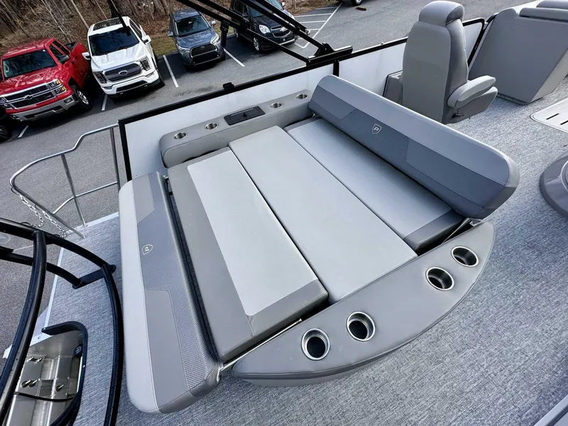Slide: The Image of 2024 Premier 250 Solaris RL boat with gray seating and cup holders, parked near vehicles. - 15