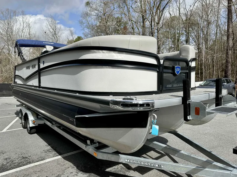 Slide: The Image of 2024 Premier 250 Solaris RL pontoon boat on trailer, parked outdoors. - 4