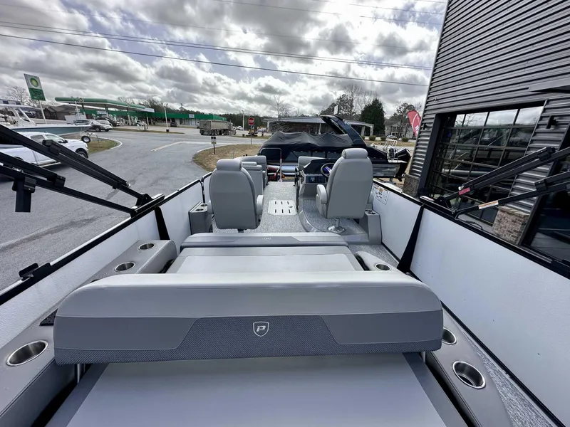 Slide: The Image of 2024 Premier 250 Solaris RL pontoon boat interior with seating and helm, parked outdoors. - 9