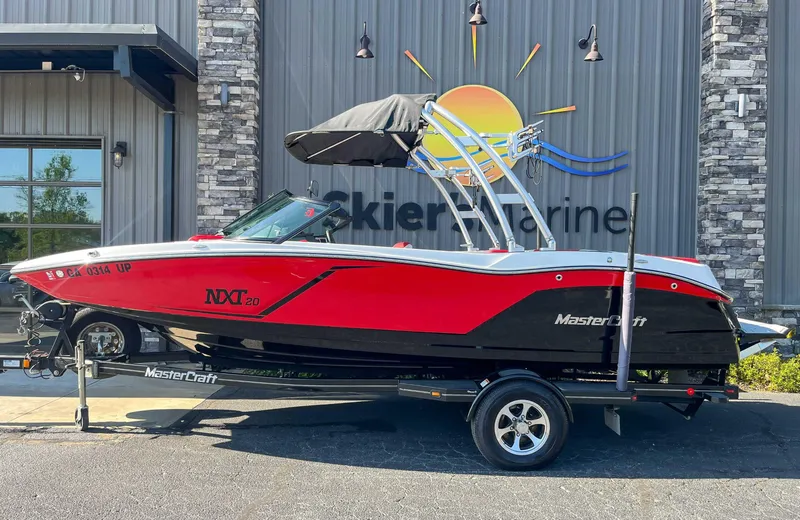 Slide: The Image of 2015 MasterCraft NXT20 boat in red and black on trailer outside dealership. - 1
