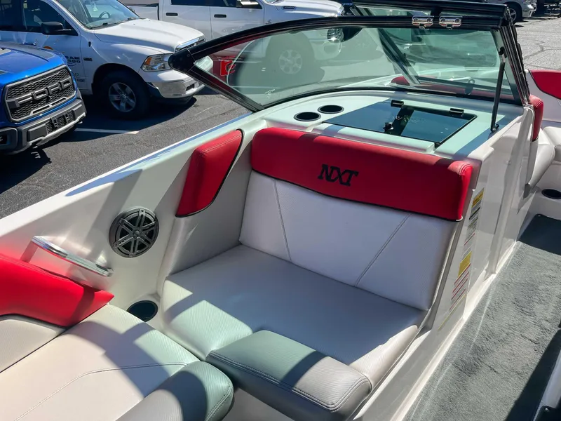 Slide: The Image of 2015 MasterCraft NXT20 boat interior with red and white seating, parked near vehicles. - 12