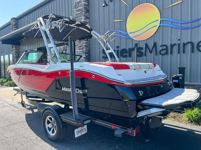 Slide: The Image of 2015 MasterCraft NXT20 boat with red and black design on a trailer outside a marine store. - 6