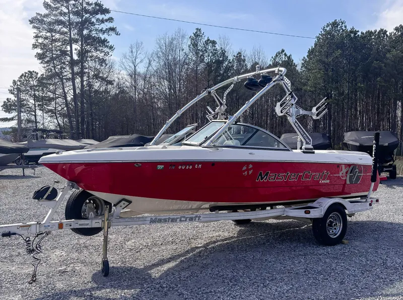 Slide: The Image of 2008 MasterCraft X1 boat in red, parked on a trailer, surrounded by trees. - 3