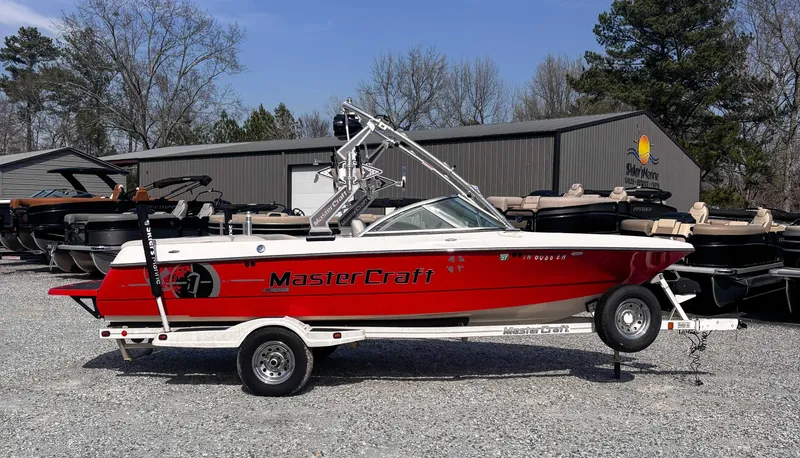 Slide: The Image of 2008 MasterCraft X1 boat in red on a trailer, parked outdoors near other boats. - 6
