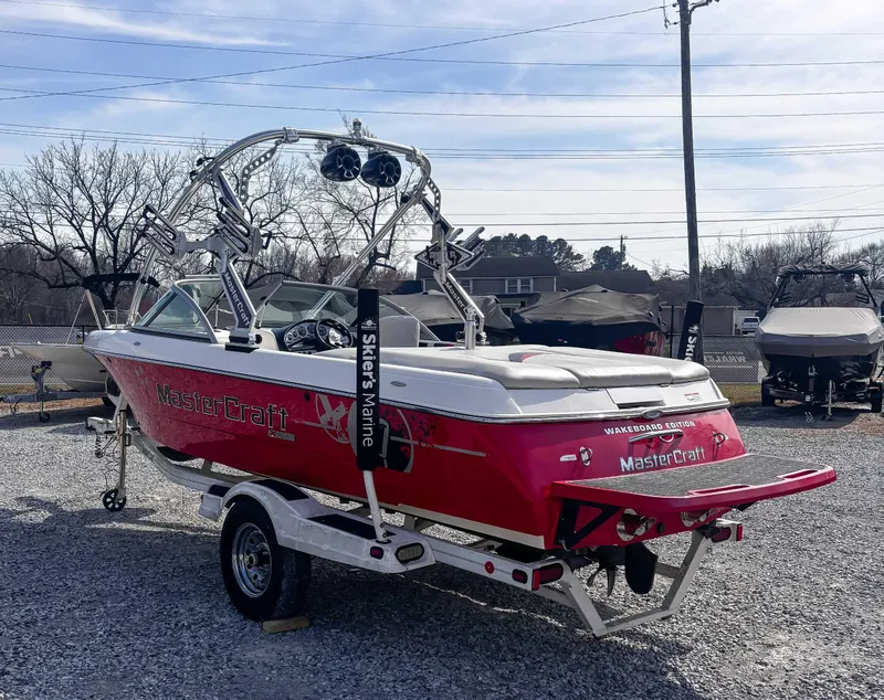 Slide: The Image of 2008 MasterCraft X1 wakeboard boat in a parking lot, featuring red and white design. - 8