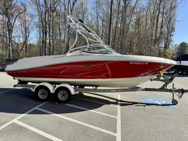 Slide: The Image of 2007 Sea Ray 230 Select boat on trailer, red and white, parked in wooded area. - 5