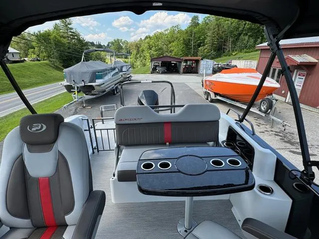 Slide: The Image of 2024 Princecraft Vogue® 23 RL pontoon boat interior with seating and table, parked outdoors. - 15