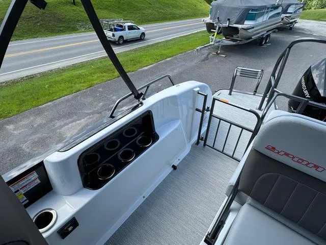 Slide: The Image of 2024 Princecraft Vogue® 23 RL boat interior with seating and cup holders, parked near a road. - 16