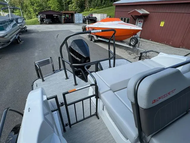 Slide: The Image of 2024 Princecraft Vogue® 23 RL pontoon boat with Mercury engine, docked near red building. - 17