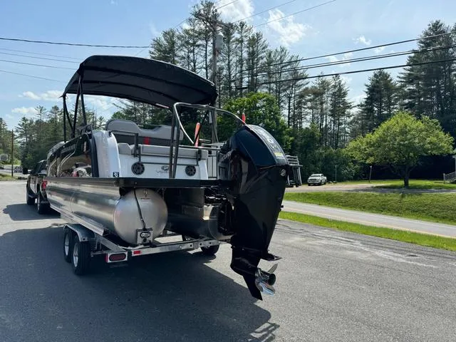 Slide: The Image of 2024 Princecraft Vogue® 23 RL pontoon boat on trailer, parked roadside with trees in background. - 8