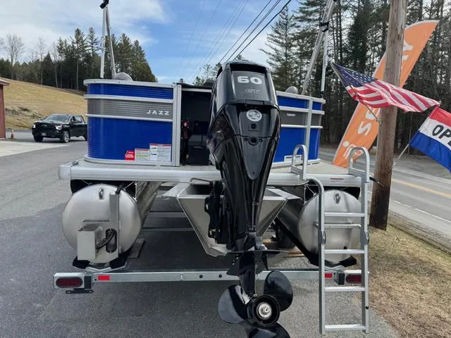 Slide: The Image of 2025 Princecraft Jazz 19-4S pontoon boat with 60HP engine, parked near flags. - 3