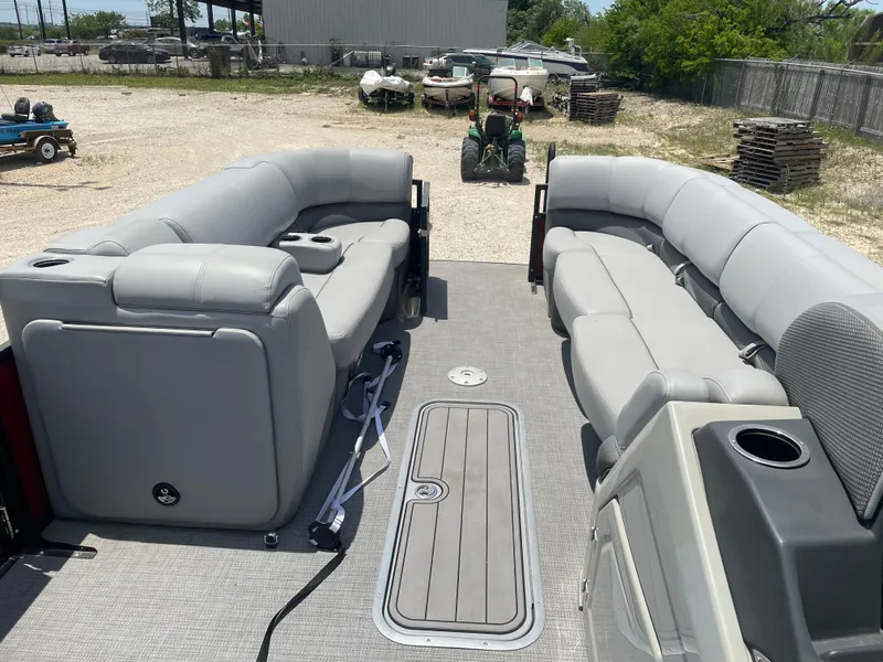 Slide: The Image of 2023 Regency 250 DL3 pontoon boat with spacious gray seating in a yard setting. - 20
