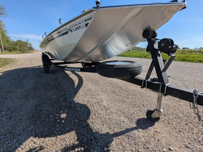 Slide: The Image of 2017 Tracker Panfish 16 boat on trailer, parked on gravel road under clear blue sky. - 10