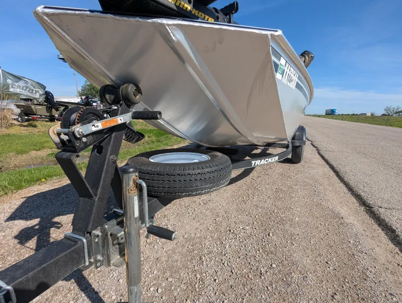 Slide: The Image of 2017 Tracker Panfish 16 boat on trailer, parked on roadside under clear blue sky. - 11