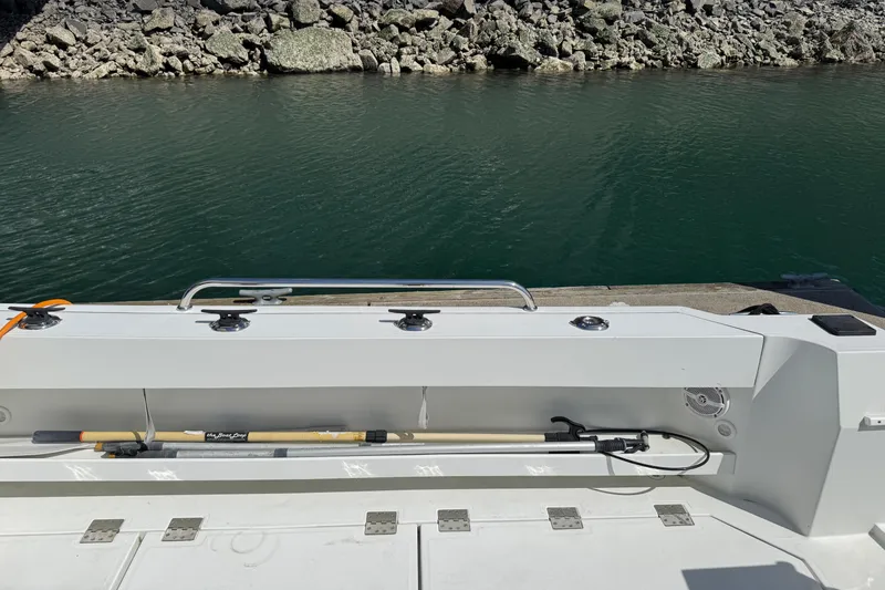 Slide: The Image of 2010 Ocean Sport Roamer boat docked by rocky shoreline, featuring a fishing rod holder. - 18