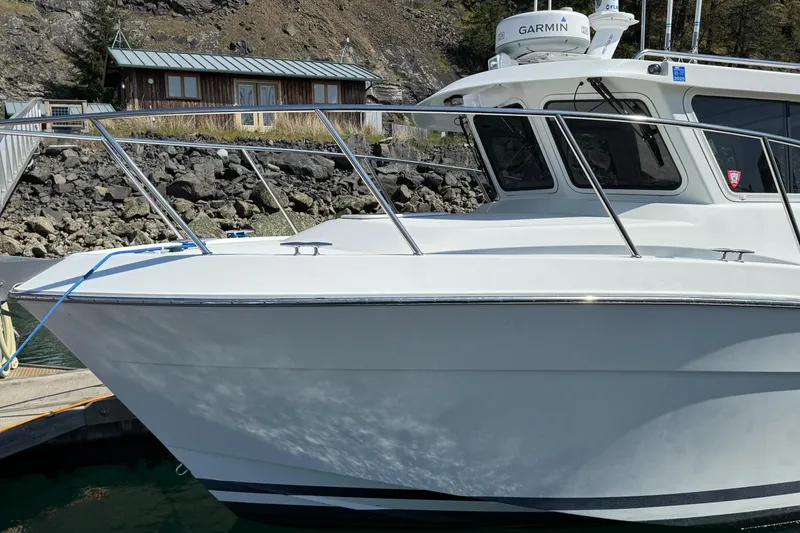 Slide: The Image of 2010 Ocean Sport Roamer boat docked near rocky shoreline. - 2