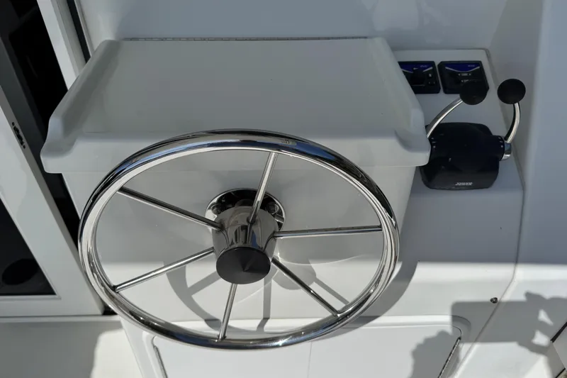 Slide: The Image of Steering wheel of a 2010 Ocean Sport Roamer boat, featuring chrome details and control levers. - 20