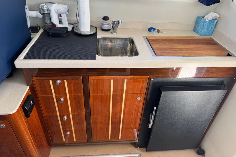 Slide: The Image of Compact kitchen area in a 2010 Ocean Sport Roamer boat with wooden cabinetry and sink. - 32
