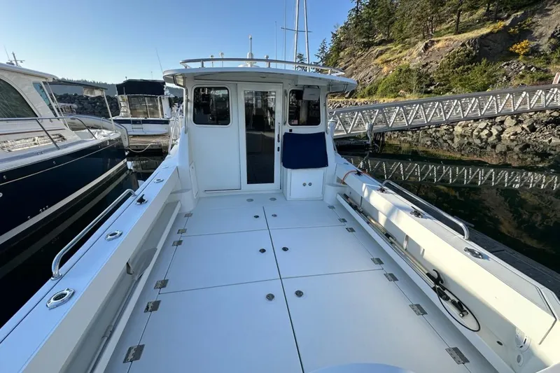 Slide: The Image of 2010 Ocean Sport Roamer boat docked, spacious deck, surrounded by water and trees. - 39