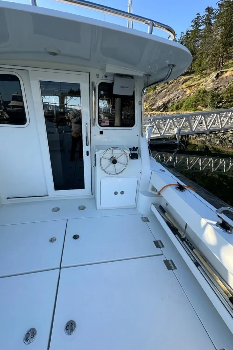 Slide: The Image of 2010 Ocean Sport Roamer boat deck with white finish, docked near rocky shoreline. - 43