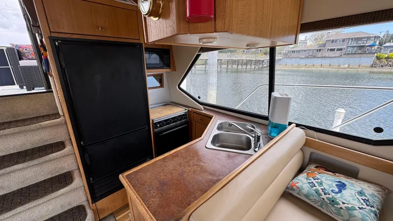 Slide: The Image of 1999 Bayliner 4087 Aft Cabin Motoryacht interior with kitchen, sink, and waterfront view. - 12