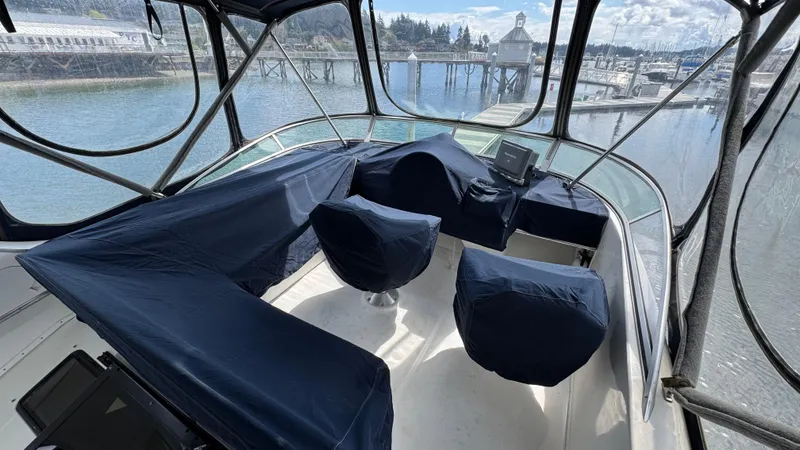 Slide: The Image of 1999 Bayliner 4087 Aft Cabin Motoryacht helm with covered seats, overlooking marina. - 2