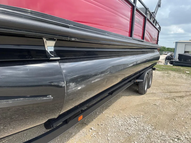Slide: The Image of 2022 Regency 250 DL3 pontoon boat on trailer, featuring red and black exterior. - 10